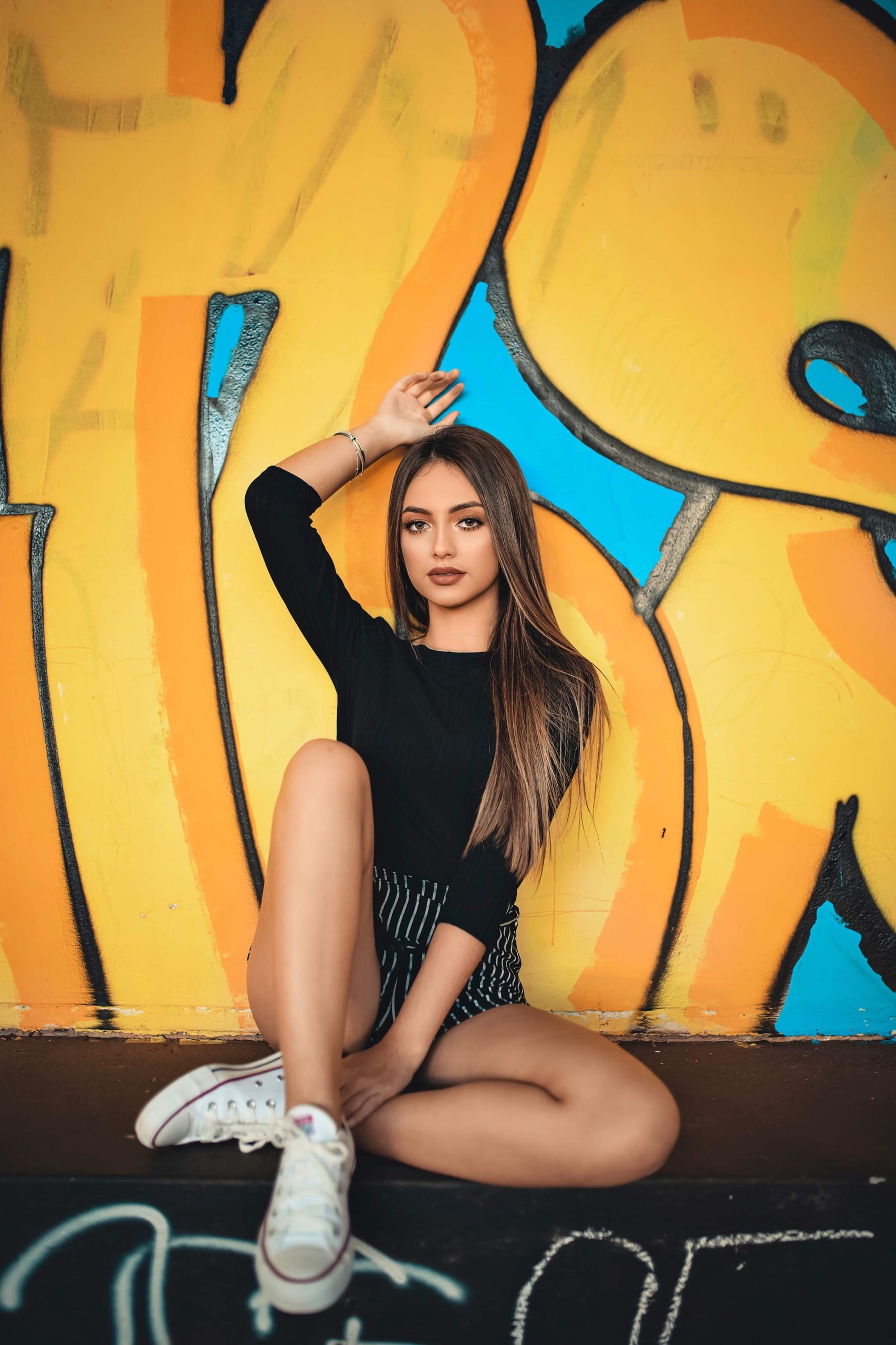 woman-sitting-up-against-graffiti-wall-2453334